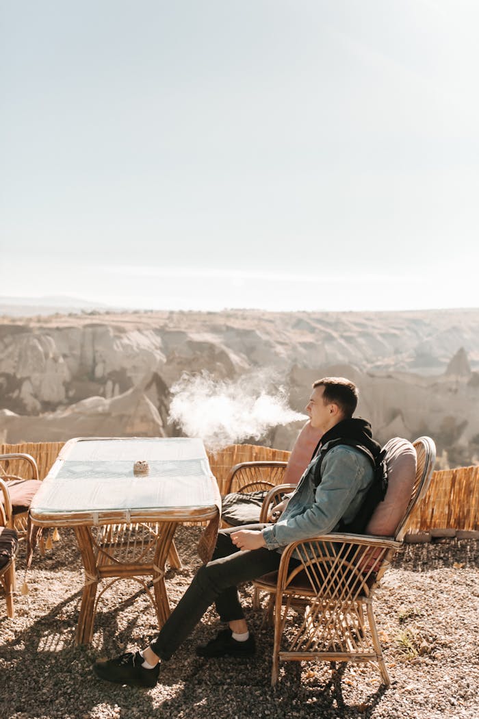 Man vaping at a scenic terrace overlooking Cappadocia's landscape, Turkey.